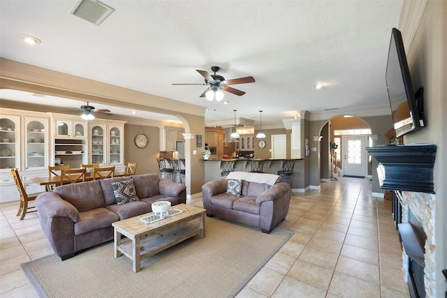 living room with ceiling fan, ornamental molding, a textured ceiling, and light tile patterned floors