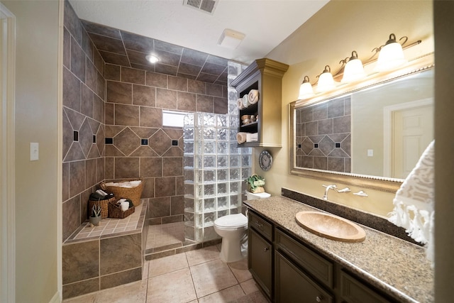 bathroom featuring tiled shower, vanity, tile patterned floors, and toilet