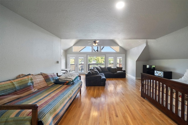 bedroom with french doors, a textured ceiling, vaulted ceiling, ceiling fan, and light hardwood / wood-style flooring