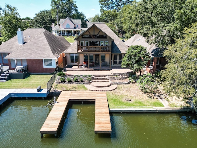 view of dock featuring a deck with water view, a patio, and a lawn