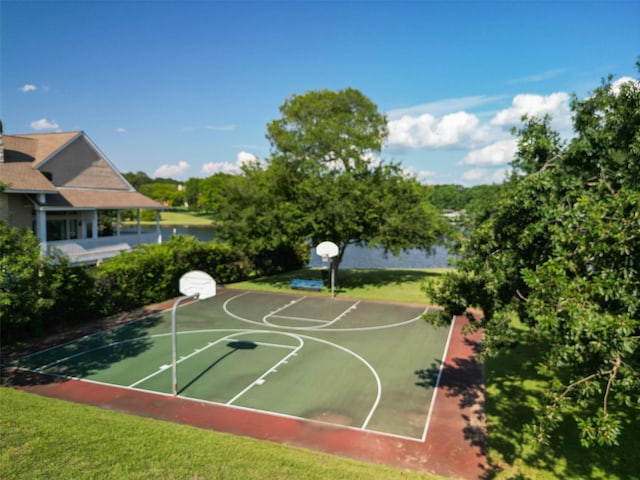 view of sport court with a lawn and a water view