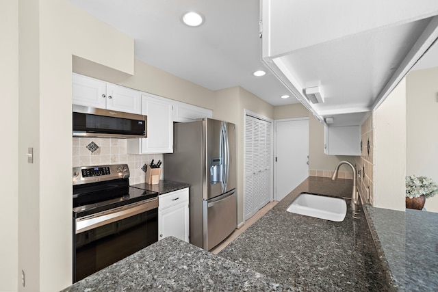 kitchen with decorative backsplash, dark stone counters, stainless steel appliances, sink, and white cabinets