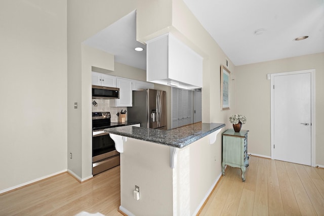 kitchen with kitchen peninsula, appliances with stainless steel finishes, light hardwood / wood-style floors, and white cabinetry