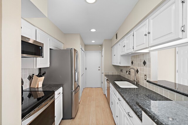 kitchen featuring appliances with stainless steel finishes, white cabinetry, dark stone counters, and sink