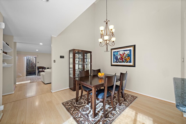 dining area with light wood-type flooring and an inviting chandelier