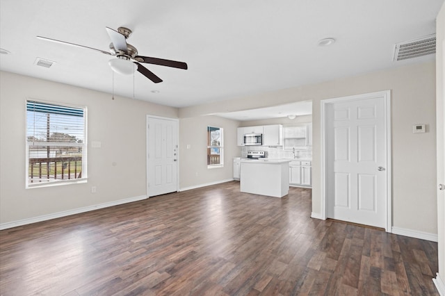 unfurnished living room featuring dark hardwood / wood-style floors, ceiling fan, and sink