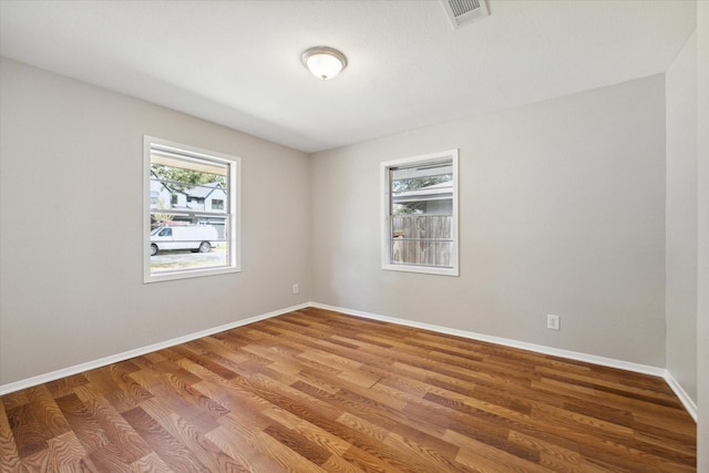 empty room featuring a healthy amount of sunlight and hardwood / wood-style floors