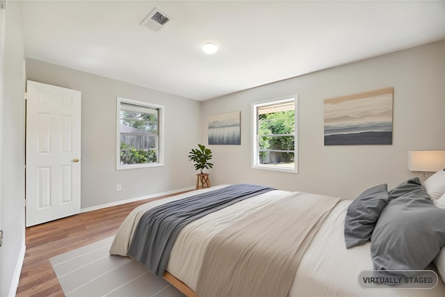 bedroom with wood-type flooring and multiple windows