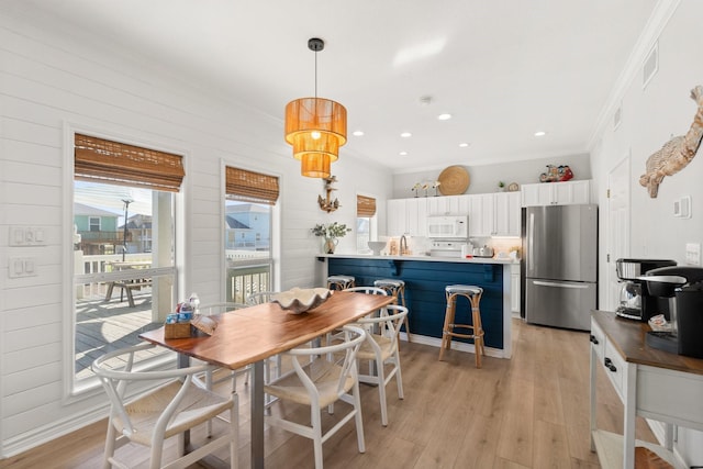 dining room featuring sink, crown molding, and light hardwood / wood-style flooring