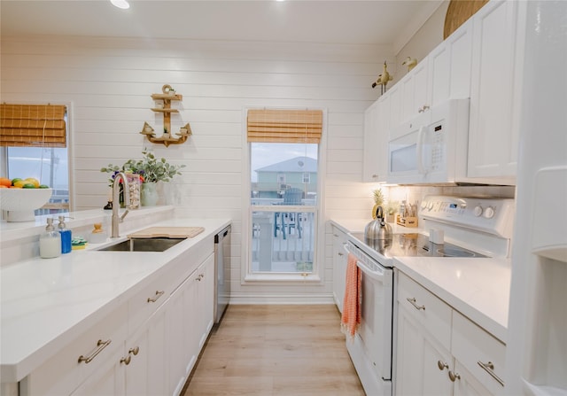 kitchen featuring white cabinets, white appliances, wooden walls, and sink