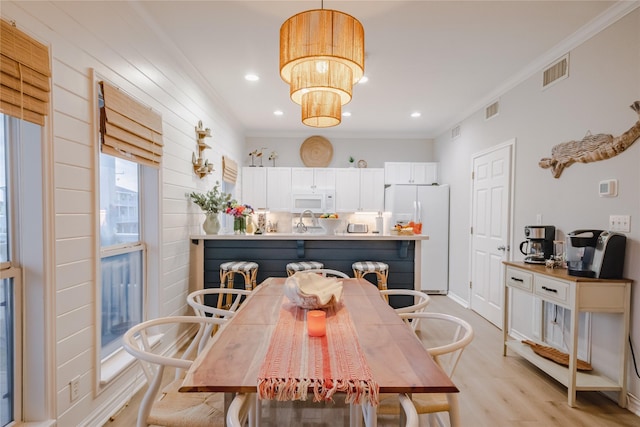 dining area with light hardwood / wood-style flooring, ornamental molding, and sink