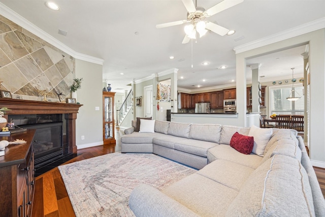 living room featuring a fireplace, dark hardwood / wood-style floors, ceiling fan, and crown molding