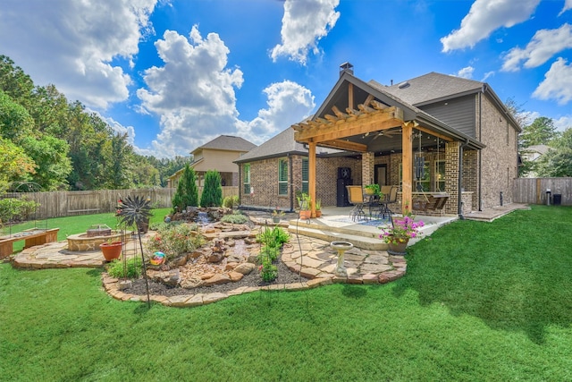 rear view of property with a pergola, a patio area, a lawn, and a fire pit