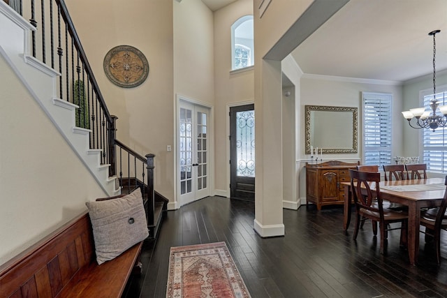 foyer with dark hardwood / wood-style floors, french doors, crown molding, and an inviting chandelier