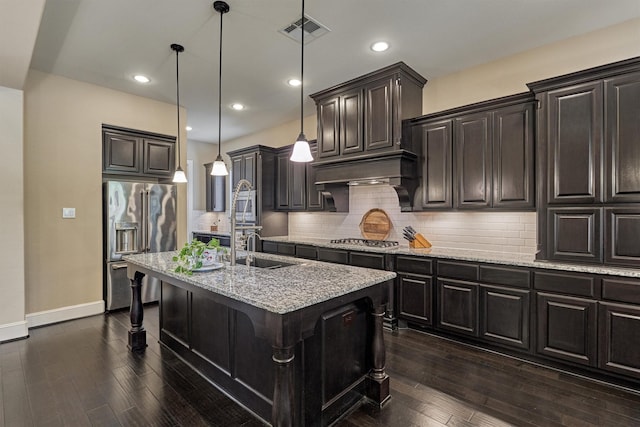 kitchen featuring a kitchen breakfast bar, pendant lighting, a center island with sink, custom range hood, and appliances with stainless steel finishes