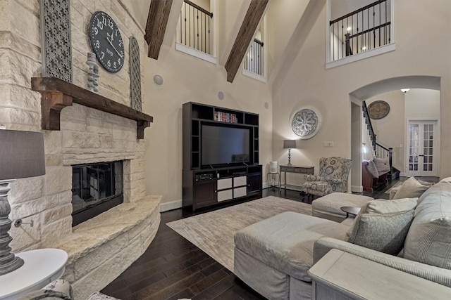 living room with beam ceiling, a fireplace, and a towering ceiling