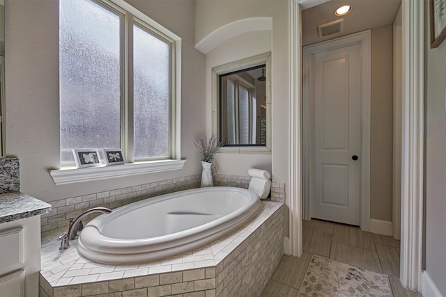 bathroom featuring vanity and a relaxing tiled tub