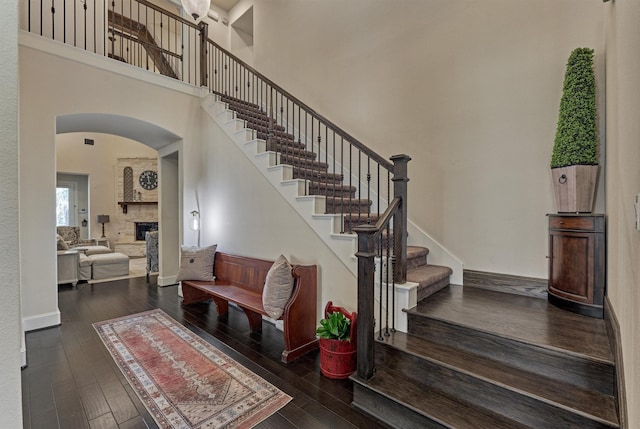 stairway with wood-type flooring and a high ceiling