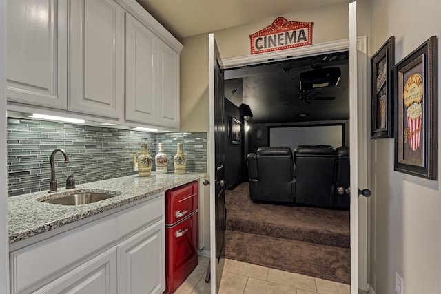 kitchen featuring white cabinets, decorative backsplash, light tile patterned floors, and sink