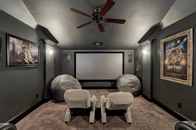 home theater featuring a textured ceiling, ornate columns, carpet flooring, and vaulted ceiling