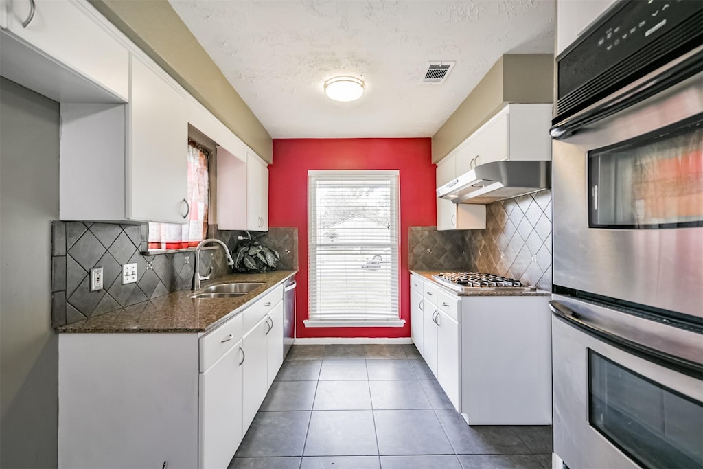 kitchen with white cabinets, stainless steel appliances, extractor fan, and sink