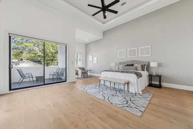 bedroom with access to exterior, a high ceiling, light wood-type flooring, and ceiling fan