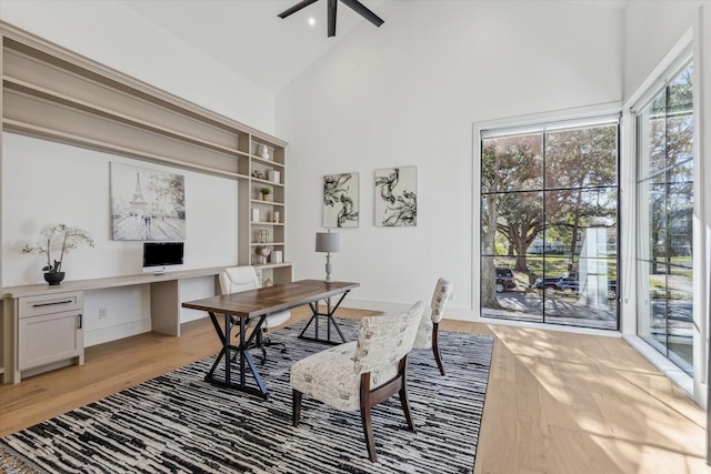 home office with built in desk, light hardwood / wood-style floors, high vaulted ceiling, and plenty of natural light