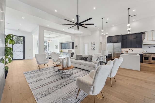 living room with ceiling fan, light hardwood / wood-style flooring, and sink