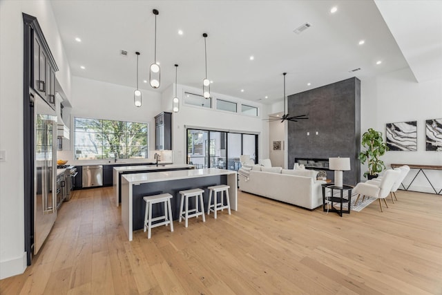 kitchen featuring pendant lighting, a towering ceiling, appliances with stainless steel finishes, and sink