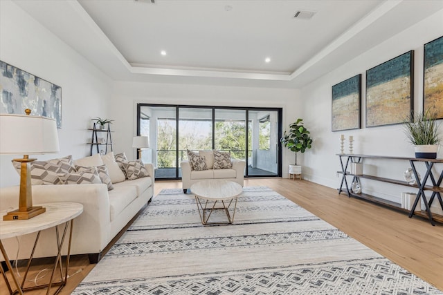 living room featuring light hardwood / wood-style flooring and a tray ceiling