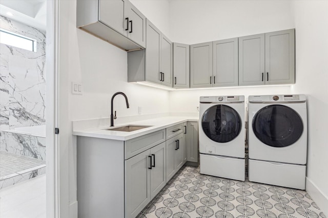 laundry area featuring washer and dryer, cabinets, and sink