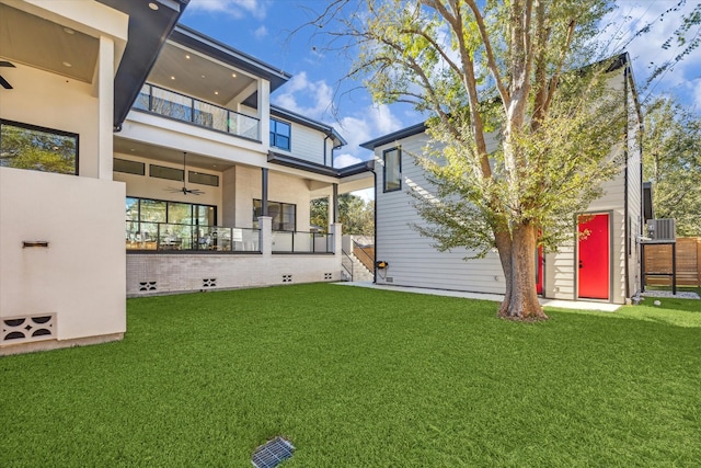 back of house with a balcony, central AC, and a lawn