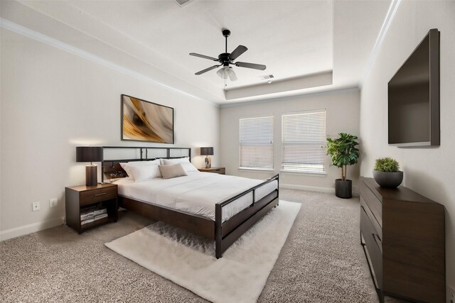 bedroom with light carpet, ceiling fan, a tray ceiling, and ornamental molding