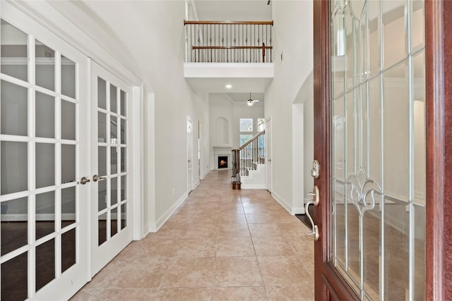 entrance foyer featuring ceiling fan, french doors, a high ceiling, and light tile patterned floors