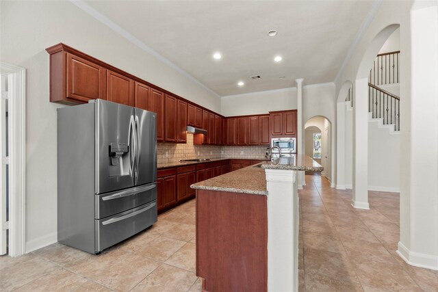 kitchen featuring light stone countertops, appliances with stainless steel finishes, sink, a center island with sink, and crown molding