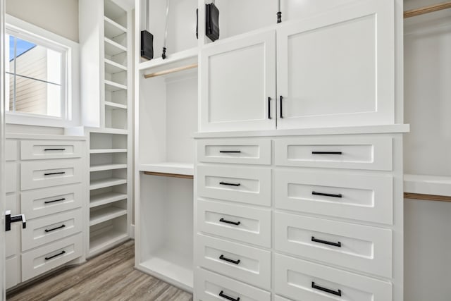 walk in closet with light hardwood / wood-style floors