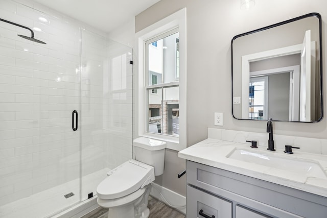 bathroom featuring vanity, toilet, wood-type flooring, and a shower with door