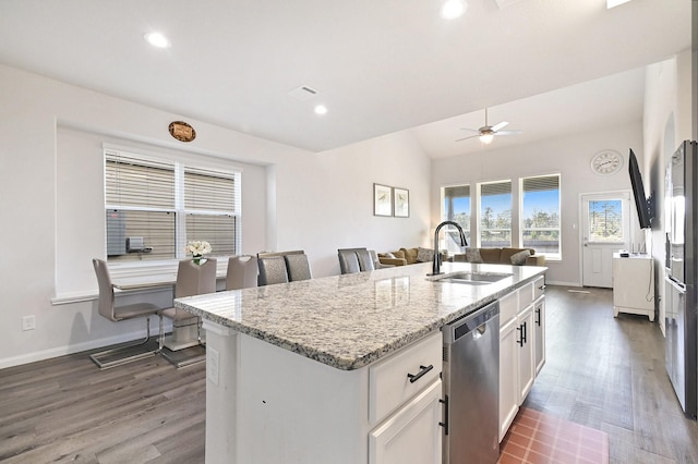 kitchen with light stone counters, sink, a center island with sink, dishwasher, and white cabinetry