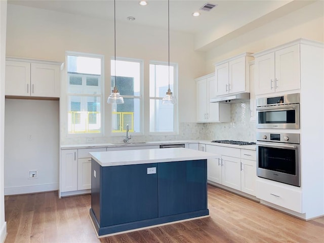 kitchen featuring a center island, white cabinets, sink, hanging light fixtures, and appliances with stainless steel finishes