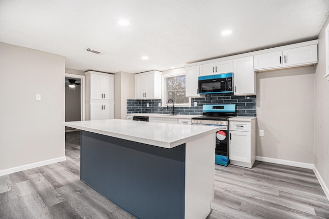 kitchen featuring sink, a center island, white cabinetry, and black appliances