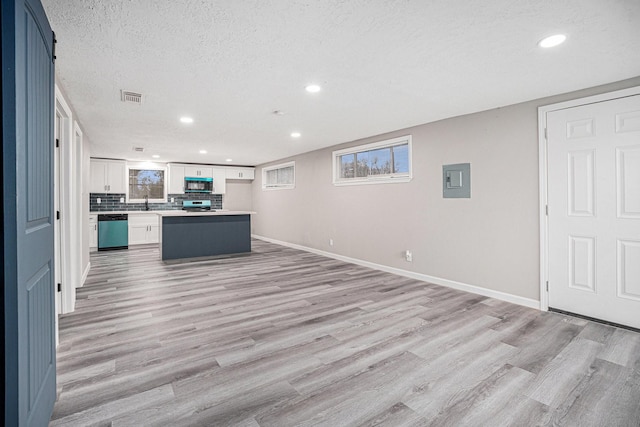 kitchen with appliances with stainless steel finishes, light wood-type flooring, a textured ceiling, a center island, and white cabinetry