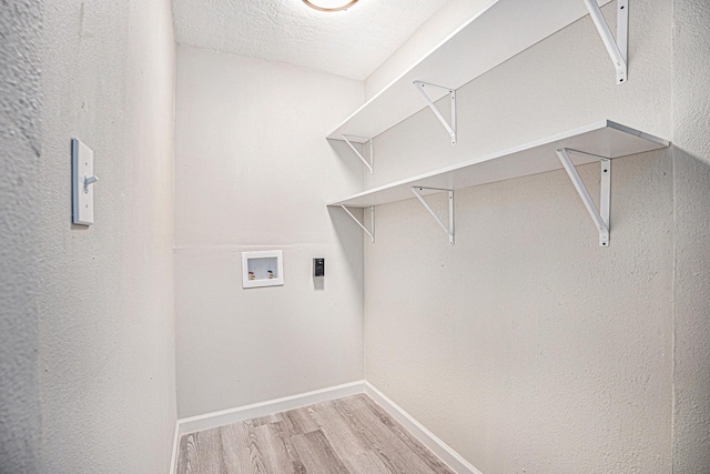 clothes washing area with hookup for a washing machine, a textured ceiling, and light hardwood / wood-style floors