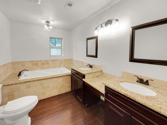 bathroom with vanity, a relaxing tiled tub, and toilet