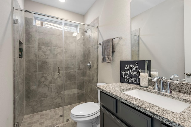 bathroom with vanity, a shower with shower door, and toilet