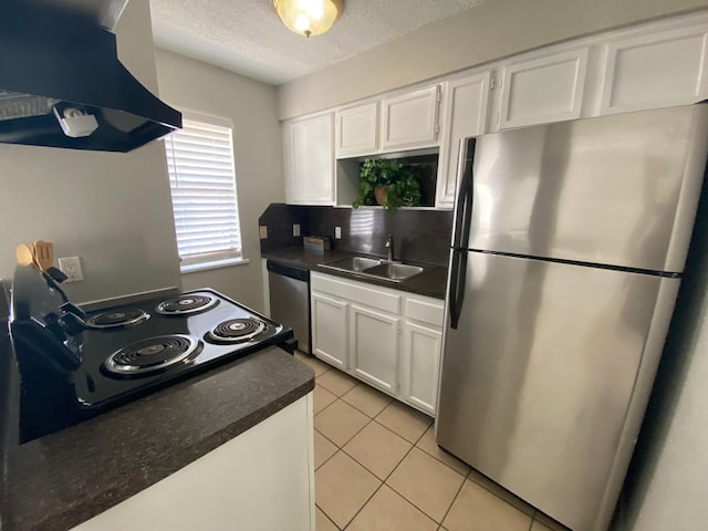 kitchen with white cabinetry, sink, range hood, light tile patterned flooring, and appliances with stainless steel finishes