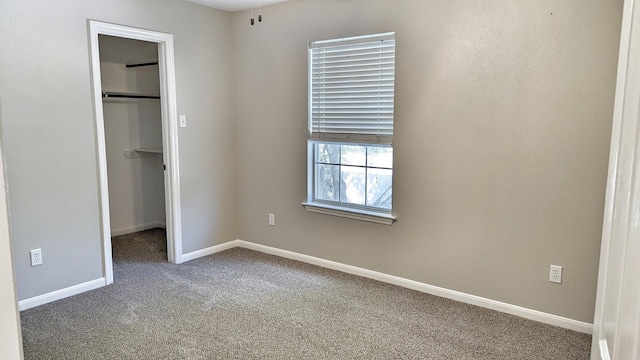 unfurnished bedroom featuring carpet, a walk in closet, and a closet