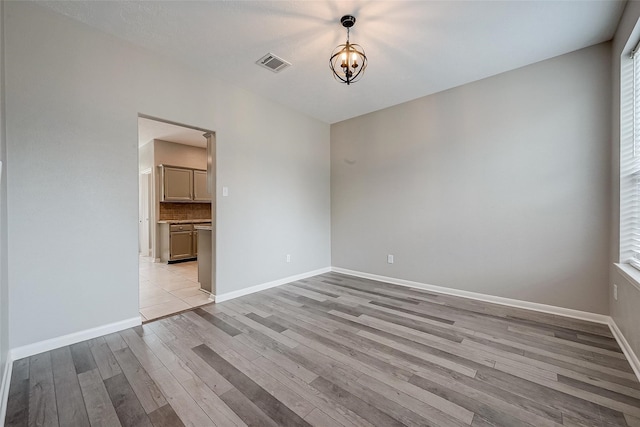 spare room featuring light hardwood / wood-style floors and an inviting chandelier