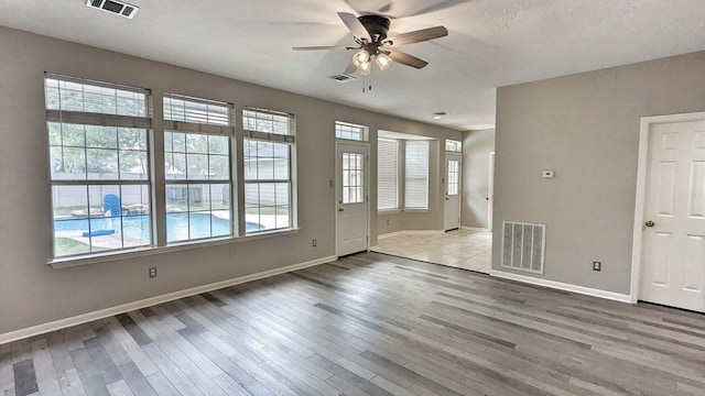 entryway with a textured ceiling, light hardwood / wood-style floors, and ceiling fan