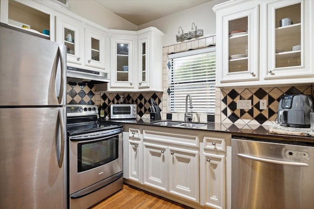 kitchen featuring appliances with stainless steel finishes, white cabinetry, dark stone countertops, and sink