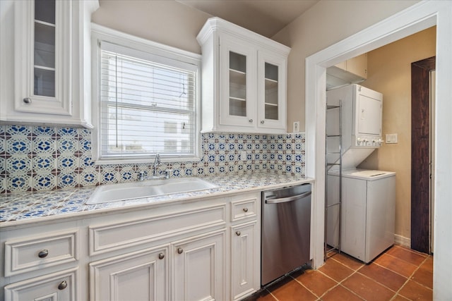 kitchen with decorative backsplash, stainless steel dishwasher, sink, white cabinets, and stacked washer / drying machine